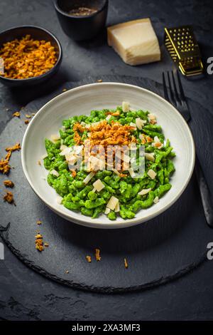 Nouilles aux œufs allemandes - spaetzle aux épinards avec parmesan et oignons rôtis Banque D'Images