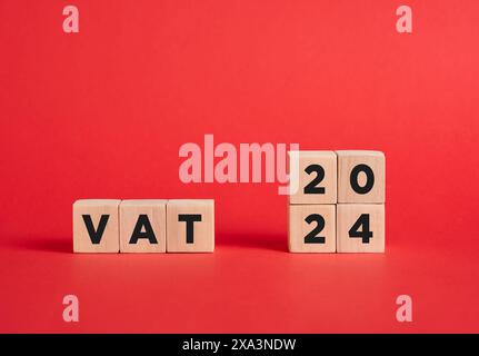 L'abréviation TVA taxe sur la valeur ajoutée pour l'année 2024 sur les cubes en bois avec fond rouge. Banque D'Images