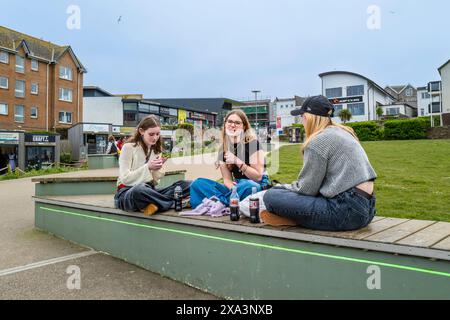 Un groupe de trois amies adolescentes assis sur un siège discutant dans la région de Killacourt dans le centre-ville de Newquay en Cornouailles au Royaume-Uni. Banque D'Images