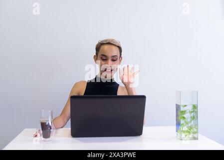 Portrait d'un bel homme asiatique de soutien de la communauté LGBT queer avec moustache portant rouge à lèvres et combinaison travaillant dans le bureau, le café et les cahiers sur Banque D'Images