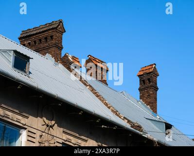 Anciennes cheminées en briques sur le toit d'une maison sur le fond d'un ciel bleu sans nuages par une journée ensoleillée Banque D'Images