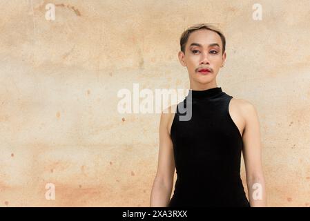 Portrait d'un bel homme asiatique de soutien de la communauté LGBT queer avec moustache portant rouge à lèvres et combinaison sur fond de mur beige Banque D'Images