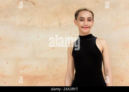 Portrait d'un bel homme asiatique de soutien de la communauté LGBT queer avec moustache portant rouge à lèvres et combinaison souriant sur fond de mur beige Banque D'Images