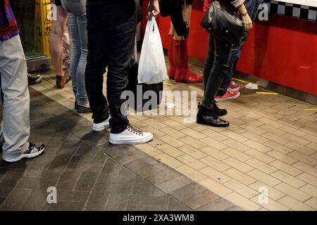 Le langage corporel des personnes qui font la queue à un comptoir de restauration rapide est indiqué par le bas du corps, les jambes, la posture, les jeans, les chaussures et la distance les unes des autres Banque D'Images