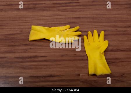 Paire de gants de nettoyage en caoutchouc jaune isolés sur fond de bois. Banque D'Images