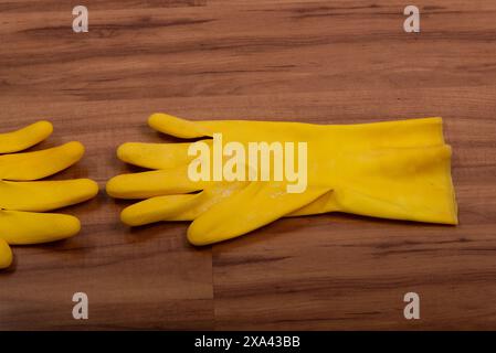 Paire de gants de nettoyage en caoutchouc jaune isolés sur fond de bois. Banque D'Images