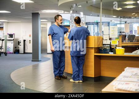 Travailleurs de la santé conversant à la réception d'un hôpital, cabinet médical Royaume-Uni Banque D'Images