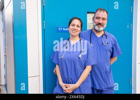 Personnel médical debout à l'extérieur d'une clinique devant un scanner CT Banque D'Images