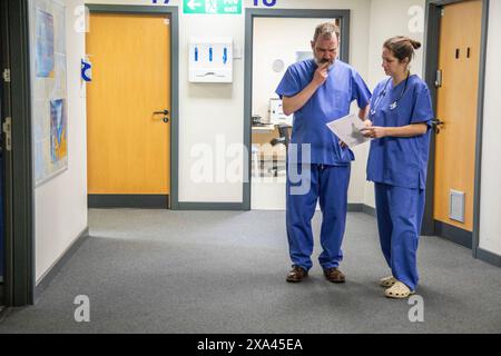Deux travailleurs de la santé consultant dans le couloir de l'hôpital, cabinet médical Royaume-Uni Banque D'Images