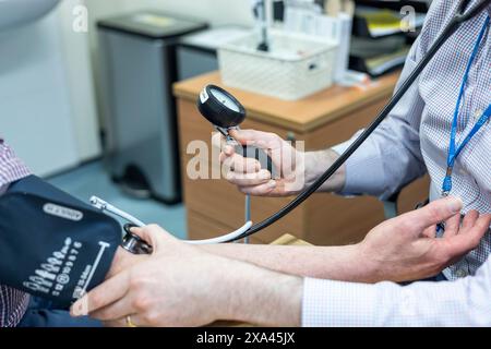 Médecin prenant la mesure de la pression artérielle pour un patient. Banque D'Images