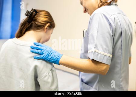 Le professionnel de la santé palpant le dos d'un patient sur une balance dans un cabinet médical Banque D'Images