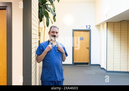 Homme en gommage bleu souriant dans un couloir d'un cabinet médical Banque D'Images