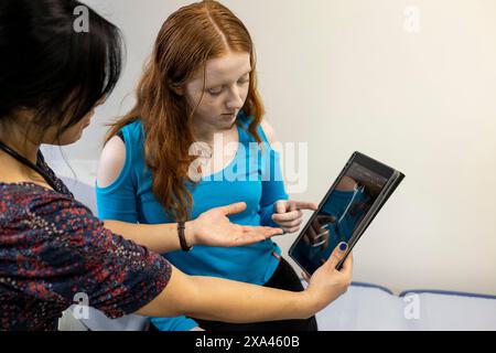 Médecin et patient examinant une radiographie sur tablette dans un cabinet médical Banque D'Images