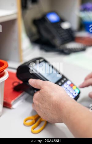 Main actionnant une machine de paiement par carte dans un cabinet médical Banque D'Images