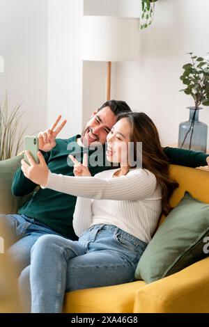 Couple prenant un selfie sur un canapé jaune. Banque D'Images