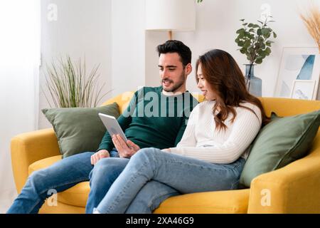 Couple se relaxant sur un canapé avec une tablette Banque D'Images