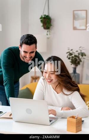 Femme souriante utilisant un ordinateur portable avec l'homme penché sur Banque D'Images