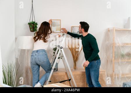 Couple disposant un cadre photo sur un mur Banque D'Images