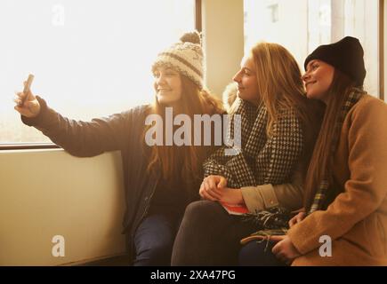 Teenage Girls Sitting on train Prendre Selfies Banque D'Images