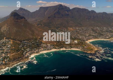 Vue aérienne d'une ville côtière avec toile de fond montagneuse et eaux turquoise limpides. Banque D'Images