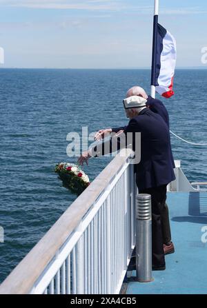 Les vétérans du jour J Harry Birdsall, 98 ans, et Alec Penstone (avant), 98 ans, jettent une couronne à la mer pendant le service de pose de couronnes du Spirit of Normandy Trust juste au large des côtes françaises, pour se souvenir de ceux qui n'ont jamais atteint le rivage, à bord du Mont St Michel. Le Brittany Ferries navigue du port de Portsmouth au Royaume-Uni à Ouistreham, à Caen, en France, transportant 31 vétérans du jour J et de la Normandie qui voyagent avec la Royal British Legion et Spirit of Normandy Trust pour participer aux commémorations marquant le 80e anniversaire du jour J. Date de la photo : mardi 4 juin 2024. Banque D'Images