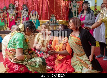 Lors d'un service Valaikappu, sa coutume est de mettre un bindi sur le front de la mère pour être. Dans un temple du Queens, New York. Banque D'Images