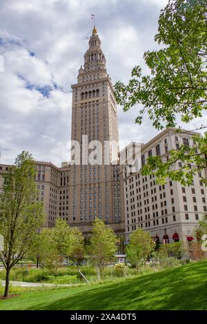 L'image montre un grand bâtiment historique avec une tour proéminente, sur fond de ciel partiellement nuageux et encadré par des arbres verdoyants au premier plan. Banque D'Images