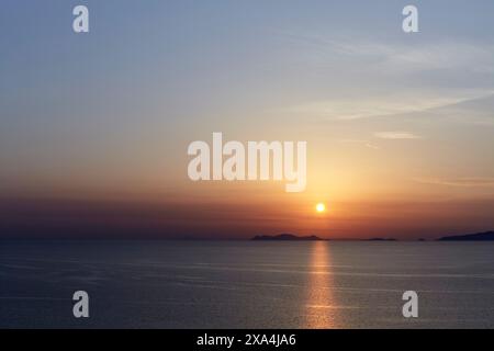 Coucher de soleil sur une mer calme avec des îles silhouettées contre le ciel. Banque D'Images