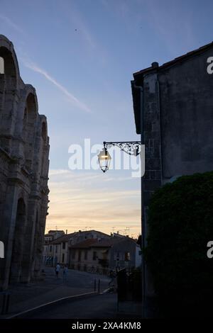 Un lampadaire à l'ancienne se silhouette contre un ciel crépusculaire à côté d'un ancien bâtiment en pierre avec un soupçon de feuillage. Banque D'Images