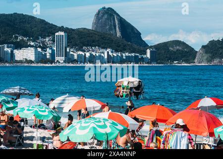 Homme vendant des maillots de bain à Copacabana Beach avec la montagne emblématique de pain de sucre en arrière-plan lointain, Rio de Janeiro, Brésil, Amérique du Sud Copyright : Alexandre Banque D'Images