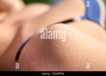 Gros plan d'une jeune femme épaule et du bras avec des gouttelettes d'eau sur la peau, portant un vêtement bleu et blanc. Banque D'Images