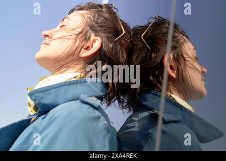 Gros plan d'une jeune femme avec le vent dans les cheveux portant des vestes bleues assorties Banque D'Images