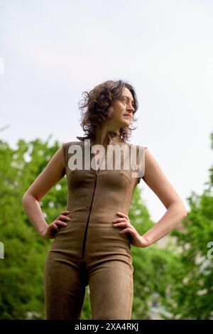 Femme confiante debout à l'extérieur dans une combinaison marron élégante. Banque D'Images
