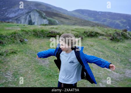 Jeune enfant profitant du vent sur un paysage de campagne vallonné. Banque D'Images