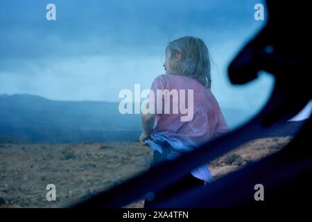 L'enfant regarde un ciel orageux depuis le siège arrière d'une voiture Banque D'Images