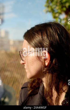 Vue de profil d'une femme avec des lunettes regardant au loin. Banque D'Images