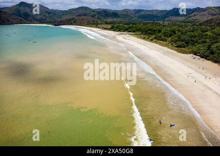 Surfeurs sur la plage et dans l'océan à Selong Belanak, Lombok, Indonésie Banque D'Images