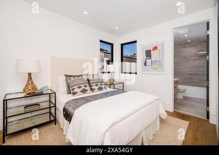 Cette chambre bien rangée présente des murs blancs et du parquet Banque D'Images