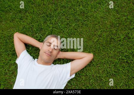 Homme mûr allongé sur l'herbe. Banque D'Images