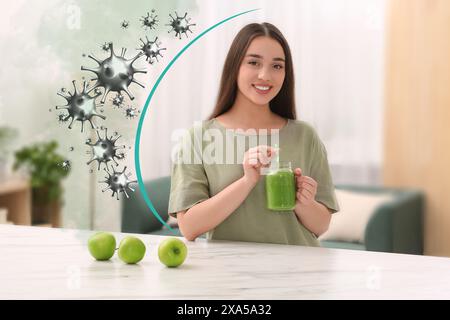 Femme heureuse avec cocktail stimulant l'immunité dans la cuisine. Protection contre les virus Banque D'Images