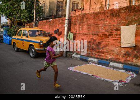 Kolkata, Inde. 03 juin 2024. Une fille court avec un ballon de football tandis qu'un taxi jaune est garé sur une route avant le dépouillement final de l'élection générale (Lok-SABHA) en Inde. (Photo de Dipayan Bose/SOPA images/SIPA USA) crédit : SIPA USA/Alamy Live News Banque D'Images