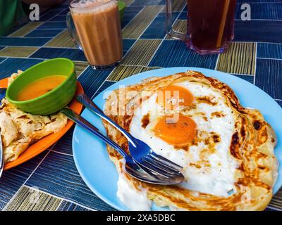 Roti sarang Burung, un pratha ressemble à un nid d'oiseau avec des œufs à moitié cuisinés au milieu servis avec Teh tarik comme aliment de base du petit déjeuner en Malaisie. Banque D'Images