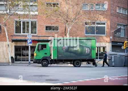 Vue latérale d'un camion de livraison de bière Heineken vert arrêté sur un coin en double rangée dans la ville de Barcelone. Banque D'Images