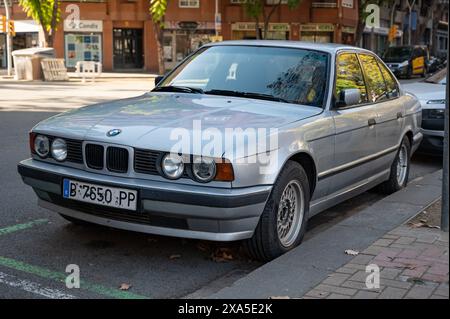 Détail avant d'une vieille voiture premium BMW 520i série 5 génération E34 en couleur argent garée dans la rue de la ville de Barcelone Banque D'Images