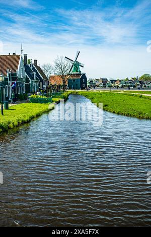 Charmante vue sur les moulins à vent historiques et les maisons hollandaises traditionnelles le long d'un canal à Zaanse Schans à Zaandam, pays-Bas. Banque D'Images