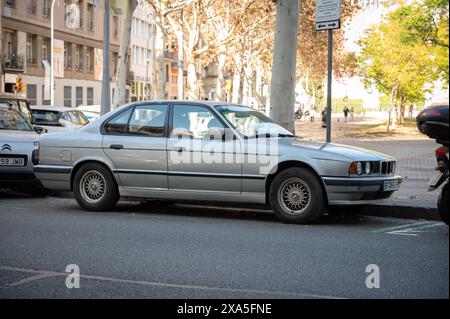 Une vieille voiture premium BMW 520i série 5 génération E34 en couleur argent garée dans la rue de la ville de Barcelone Banque D'Images