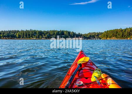 Un kayak rouge vif se dirige vers la baie de Degnen à l'extrémité sud de l'île Gabriola Banque D'Images