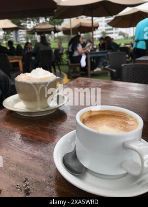 Profitez d'une pause café tranquille et confortable à l'extérieur dans un charmant café avec une table en bois, un fond flou et un délicieux espresso ou cappuccino recouvert de crème fouettée Banque D'Images