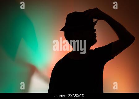Portrait studio d'un homme tenant un chapeau en silhouette. Isolé sur fond coloré. Banque D'Images