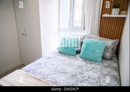 Chambre lumineuse et accueillante avec lit soigné, oreillers moelleux et décoration minimaliste Banque D'Images